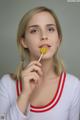 A young woman holding a lollipop in her mouth.