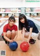 Two young women crouching down with bowling balls in their hands.