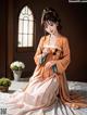 A woman in an orange kimono sitting on a bed.