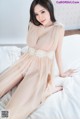 A woman in a sheer dress sitting on a bed.
