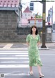 A woman in a green dress is crossing the street.