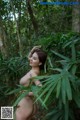 A naked woman standing in the middle of a forest.