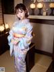 A woman in a blue kimono standing in a room.