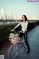 A woman riding a bike with a basket on the back.