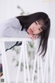 A young woman leaning on a white chair.