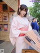 A woman in a pink kimono holding a bunch of umbrellas.