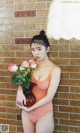 A woman in a bathing suit holding a vase of flowers.