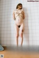 A naked woman tied up in a bathroom.