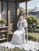 A woman in a white dress sitting on a bench.