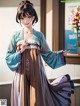 A woman in a blue and brown kimono standing in front of a window.