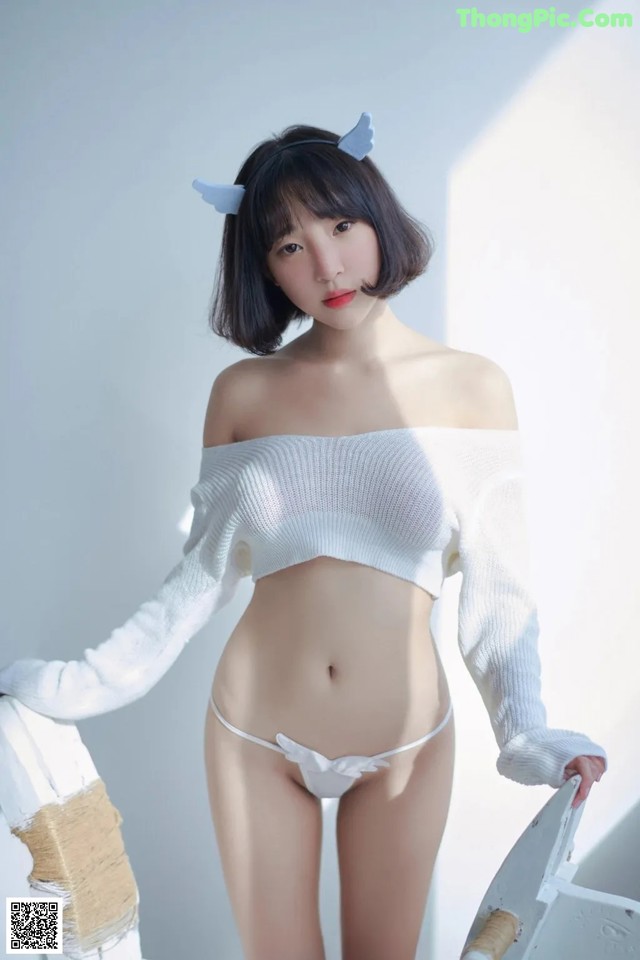 A woman in a white sweater and white panties posing for a picture.