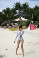 A woman in a bathing suit walking on a beach.