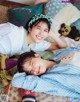 A couple of young women laying on top of a bed.