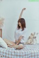 A woman sitting on a bed with a teddy bear.