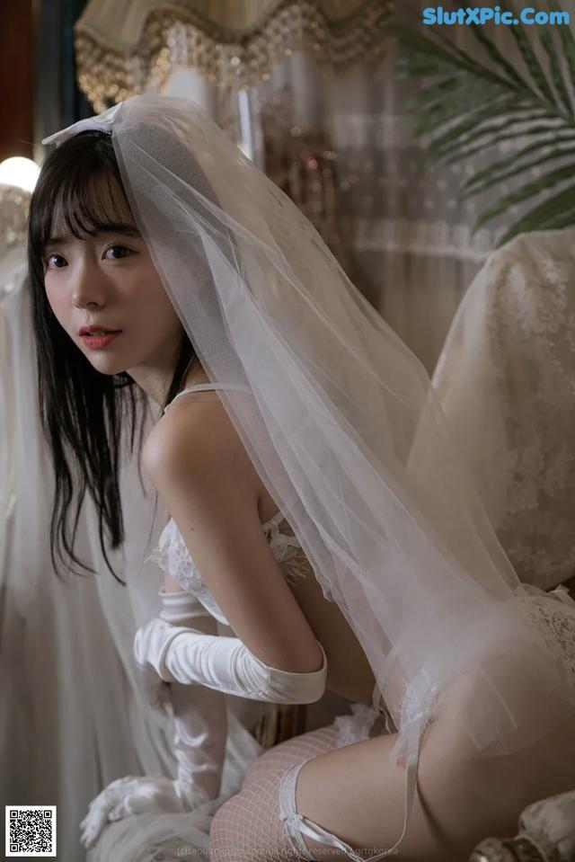 A woman in a wedding dress sitting on a chair.