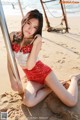 A woman in a red and white bikini sitting on the beach.