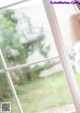 A woman in a white dress looking out a window.