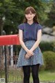 A young woman standing in front of a red mailbox.