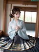 A woman in a blue and gold hanbok sitting on a bed.