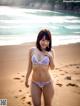 A woman in a bikini standing on a beach.